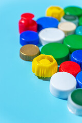 Colorful plastic bottle caps on a blue background, collecting plastic for recycling and reuse.