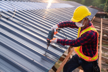 Top view Construction worker safety wear using electric drill tools install on new roof metal...