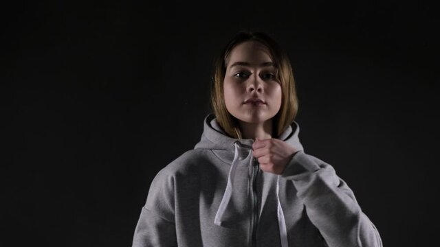 Determined woman zips up hoodie to go running in cold weather, slow motion