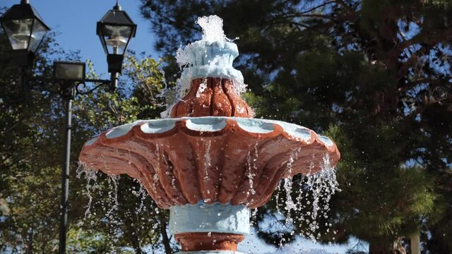 Spraying water in vintage style park fountain on sunny summer day, parallax shot
