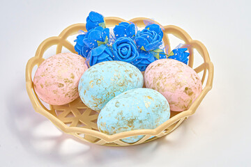 Painted Easter eggs together with flowers lie in a wicker plate.