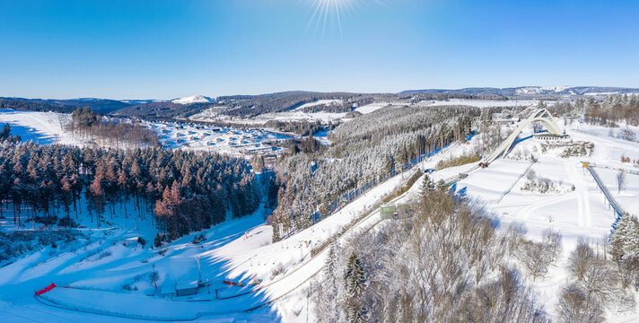 Saint George ski jump and ski slopes of Winterberg ski lift carousel photographed from the air. Panorama image of deserted winter sports area.