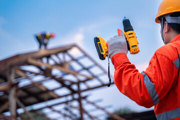 Roofing tools, Roofer worker holding electric drill used on new roofs with Metal Sheet at...