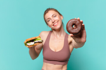 young pretty sport woman happy expression and holding a sandwich and a donut