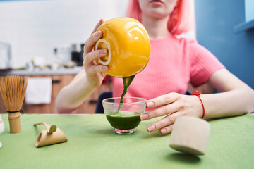 Woman with pink hair preparing freshly made matcha tea