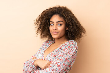 Young African American woman isolated on beige background keeping the arms crossed