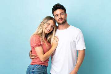 Young caucasian couple isolated on blue background laughing