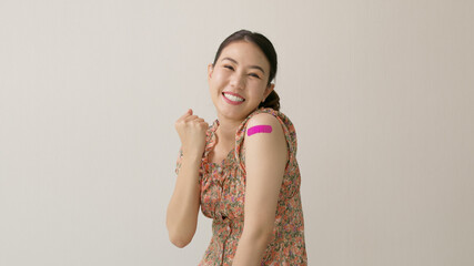 Young attractive beautiful asia female or teenage receive covid-19 anti virus vaccine in campaign vaccination safe life happy smile cheerful with blue, yellow, pink bandage on arm with copy space.