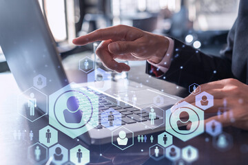Hands of hr specialist is typing the keyboard in the internet to find the best candidates to create international network in recruitment process. Formal wear. Social media hologram icons.