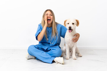 Young veterinarian woman with dog sitting on the floor shouting with mouth wide open