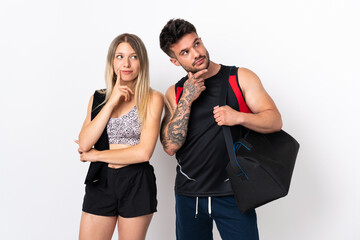 Young sport couple isolated on white background thinking an idea while looking up