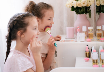 Obraz na płótnie Canvas Two sisters making make up in a bedroom. Kids beauty care concept.