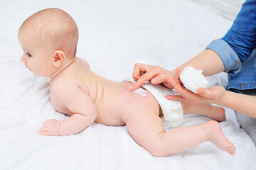 the mother's hand applies a moisturizing baby cream to the baby boy's skin. Hygiene of the newborn child.