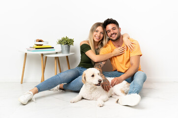 Young caucasian couple with dog staying at home hugging