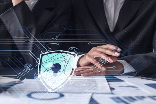 Two businesswomen working on the project to protect cyber security of international company. Padlock Hologram icons over the table with documents.