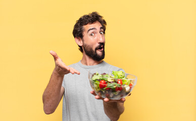 young crazy bearded man dieting surprised expression and holding a salad
