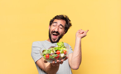 young crazy bearded man dieting celebrating successful a victory and holding a salad