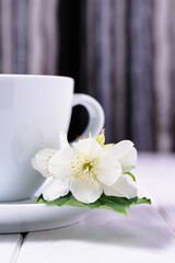 Close-up of a white porcelain cup and next to a fresh jasmine flower. Tea break.