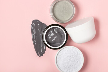 An open cosmetic jar, against the background of a smeared cream or cosmetic face mask. Purifying and moisturizing clay mask. Top view, flat lay
