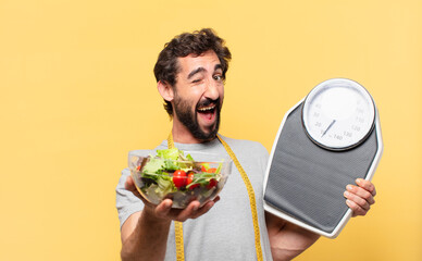 young crazy bearded man dieting happy expression and holding a scale and a salad
