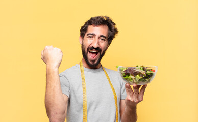 young crazy bearded man dieting celebrating successful a victory and holding a salad