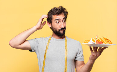 young crazy bearded man dieting thinking expression and holding waffles