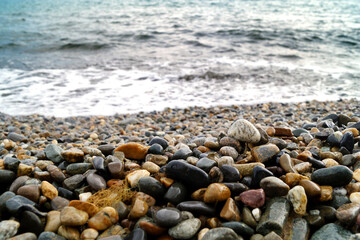 Wet small pebbles on the coast. On the background of the sea and the sea wave.
