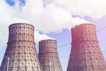 Three soaring evaporators of CHP against the background of blue sky. White cloud of industrial...