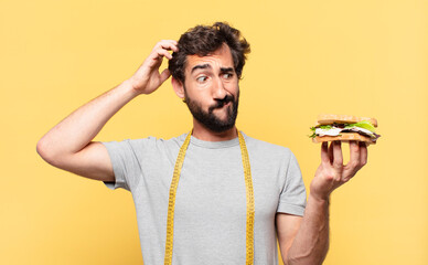 young crazy bearded man dieting thinking expression and holding a sandwich