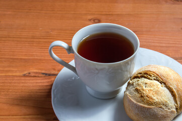 plate with cup of tea and rustic bread, isolated on wood background. Seen up close