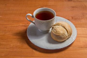 plate with cup of tea and bread, isolated on wood background.