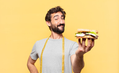 young crazy bearded man dieting happy expression and holding a sandwich