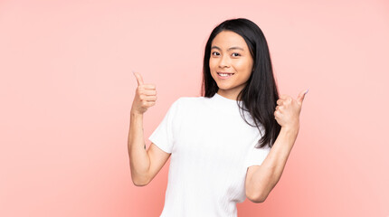 Teenager Chinese woman isolated on pink background giving a thumbs up gesture