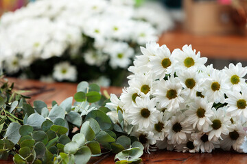 A bouquet of white chrysanthemums lies on a wooden table.