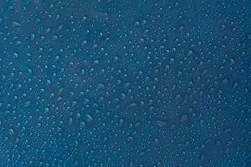 Droplet texture. Wet drop water on glass blue background.