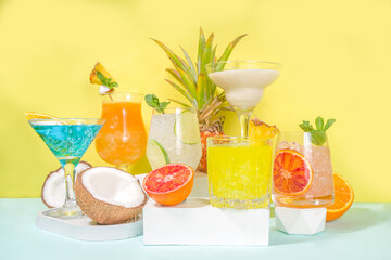 Colorful summer drinks set. Various bright alcohol cocktails and beverages, in different glasses, with tropical fruit on modern bright background copy space
