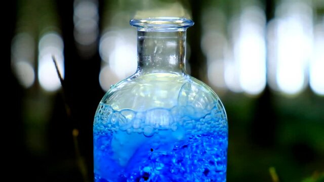 Magic potion. Boiling blue potion.herbal blue potion.Herbal elixir on a mossy stump on a blurred forest background. Homeopathic medicine. Organic Cosmetics