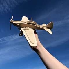 hand holding a wooden plane sky background