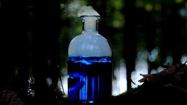 Magical blue smoking potion. herbal potion. Herbal elixir on a mossy stump on a blurred forest background.Magic Potion. Homeopathic medicine. Organic Cosmetics
