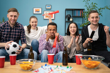 Happy friends or football fans watching soccer on tv and celebrating victory at home. Friendship, sports and entertainment concept.