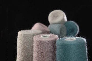 Light fluffy wool yarn on large coils.Yarn in different colors for knitting or crocheting.Natural mohair.Hobbies and crafts. Black background.Out of focus.