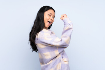 Teenager Chinese woman isolated on blue background doing strong gesture