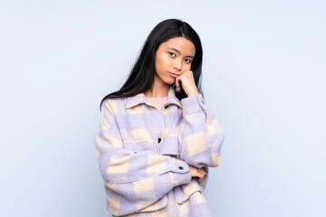 Teenager Chinese woman isolated on blue background with tired and bored expression