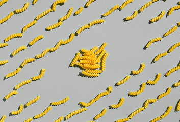 Italian fusilli, rotini or scroodle macaroni pasta food background texture. Top view, pasta spirals on gray background