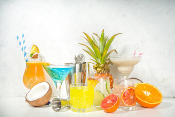 Colorful summer drinks set. Various bright alcohol cocktails and beverages, in different glasses, with tropical fruit on white background copy space