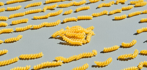 Italian fusilli, rotini or scroodle macaroni pasta food background texture. Close up, pasta spirals on gray background
