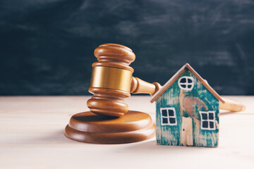 Judge gavel and houses on a wooden background. The concept of a real estate auction or division of a house in case of divorce.