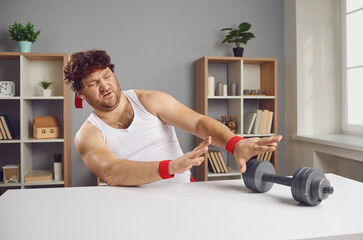 I don't want to exercise. Displeased guy pushing away fitness dumbbells. Funny lazy chubby man feeling repulsed and disgusted at sight of sports equipment unwilling to start gym training workouts