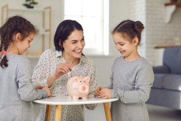 Kids learn to handle money. Mom teaches her two little daughters financial literacy and puts money...