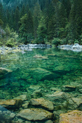 Crystal clear dark green montain lake with clear water on a moody dark rainy spring day. Alps mountains, Austria